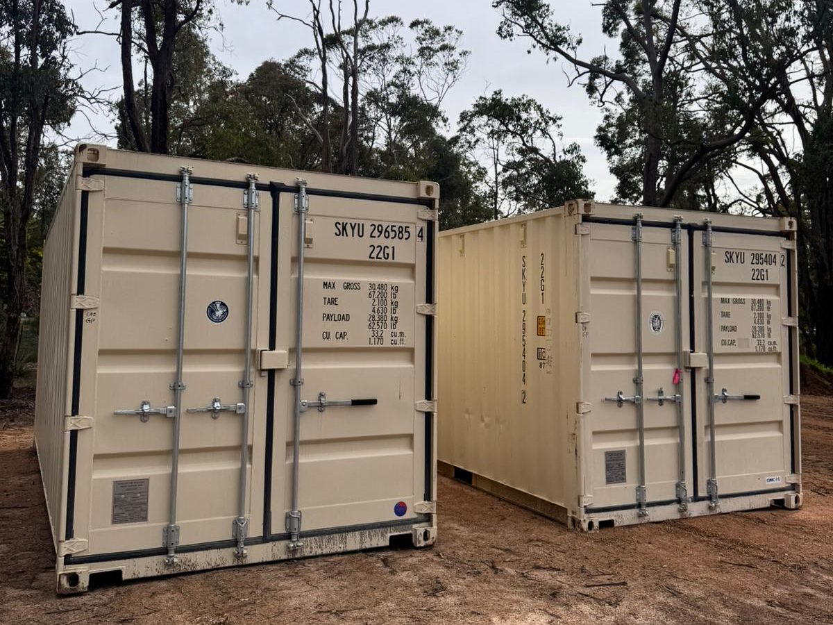 Two Stock'n Lock 20ft containers side by side, showing the full external size against the surrounding trees
